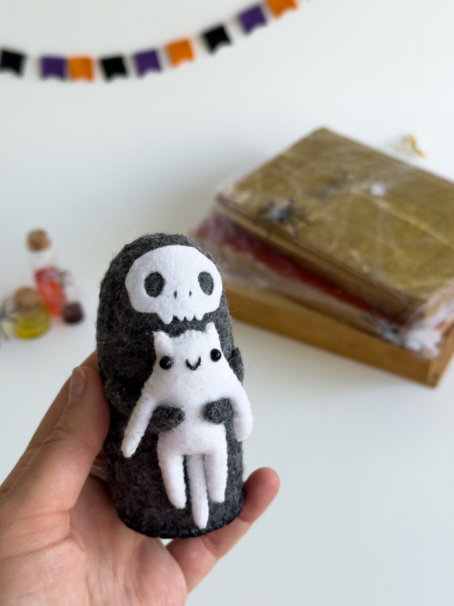 Close-up of Grim Reaper Halloween plush with tiny smiling white cat