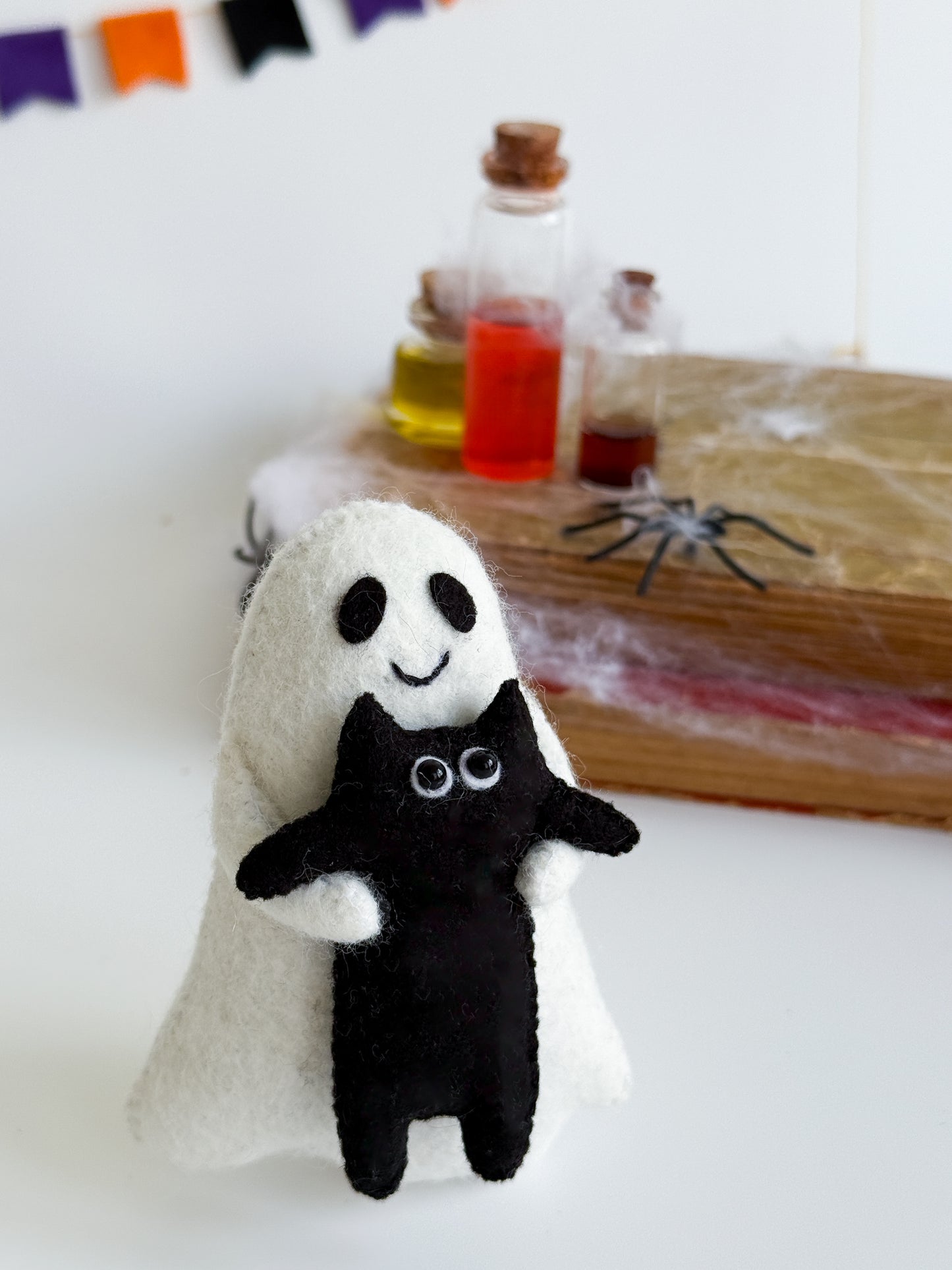 Ghost plush toy with stitched smile and hugging black kitty