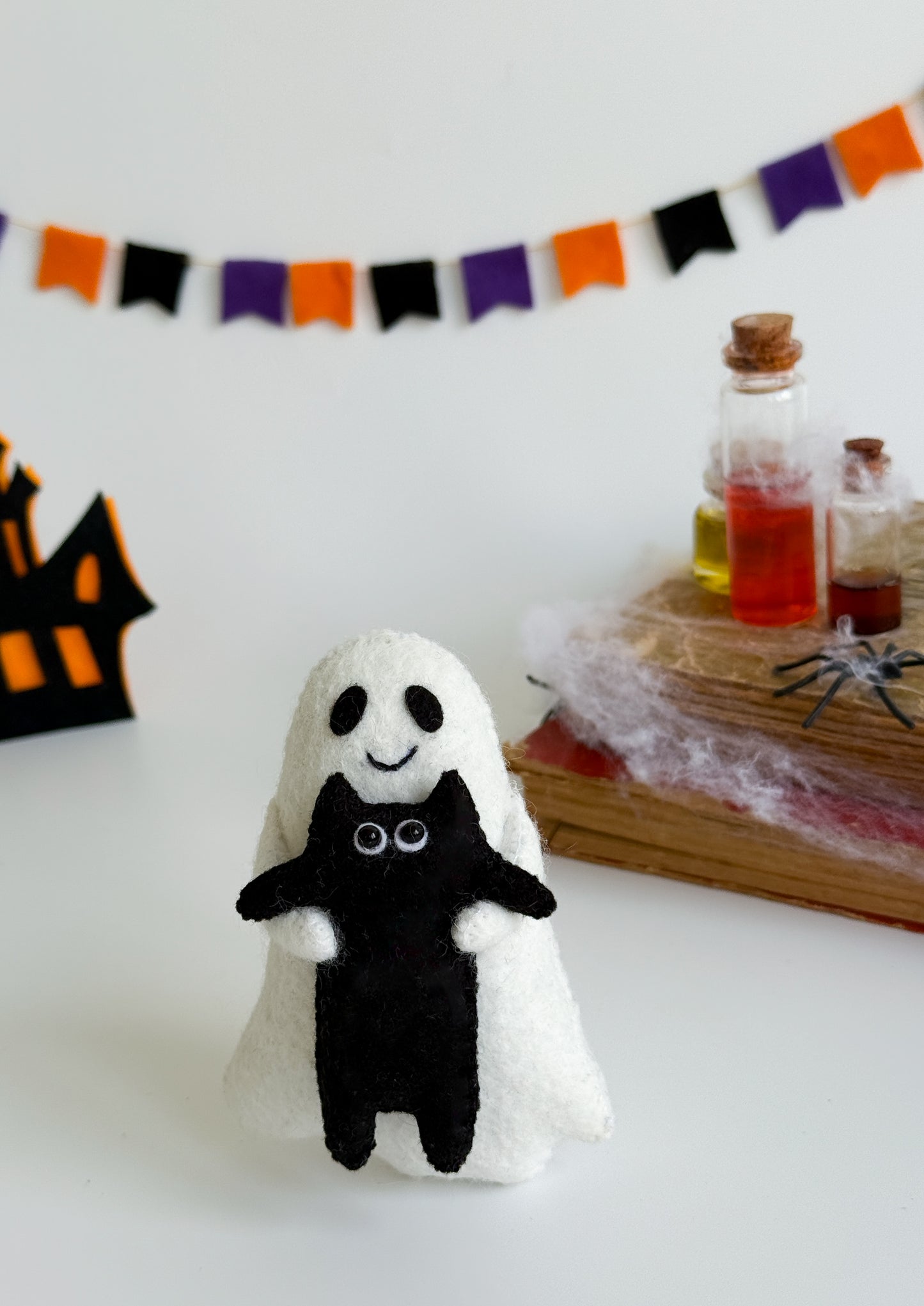 Ghost plush toy with stitched smile and hugging black kitty