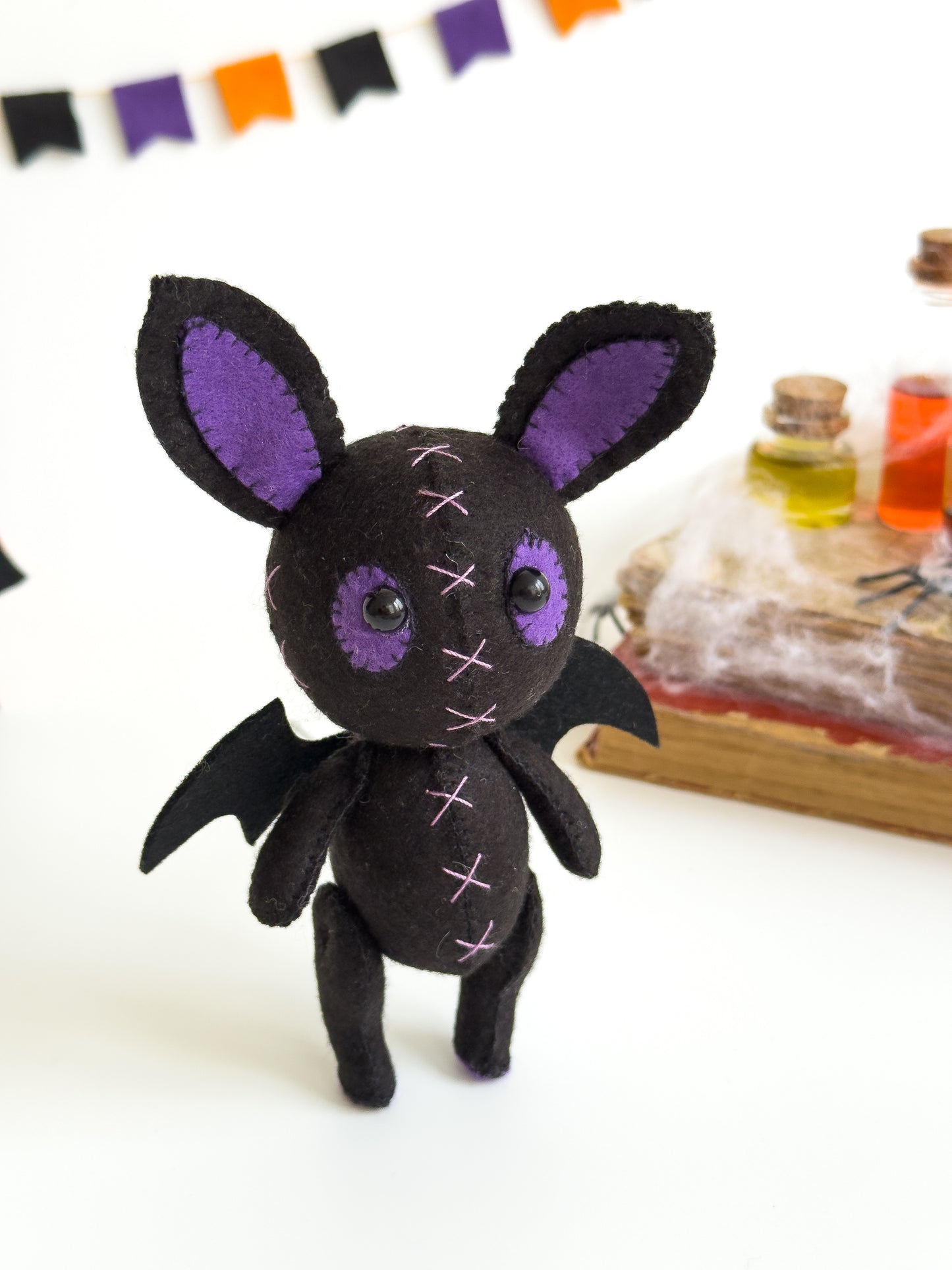 Handmade felt bat plush with purple ears and stitched crosses