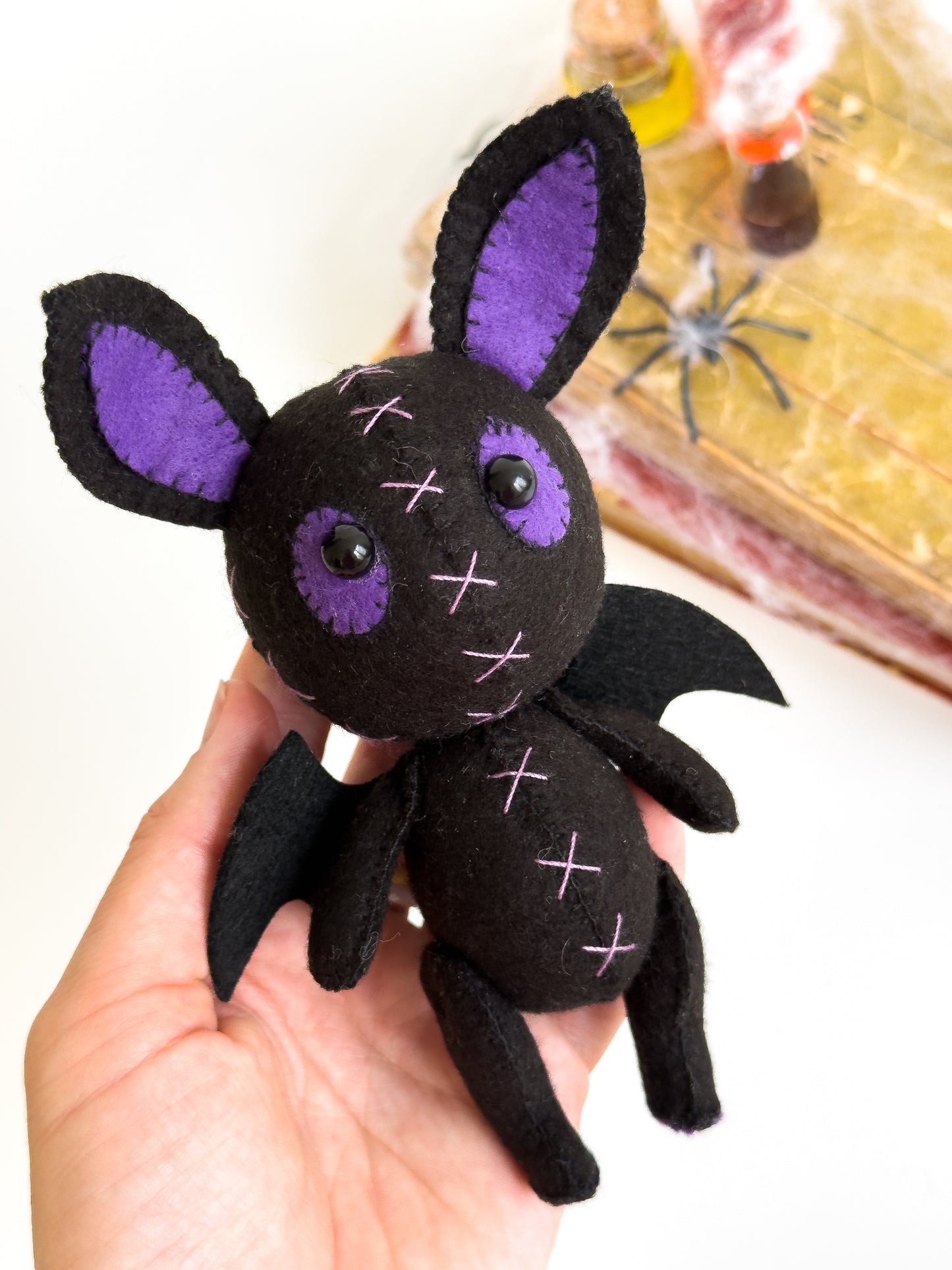Handmade felt bat plush with purple ears and stitched crosses