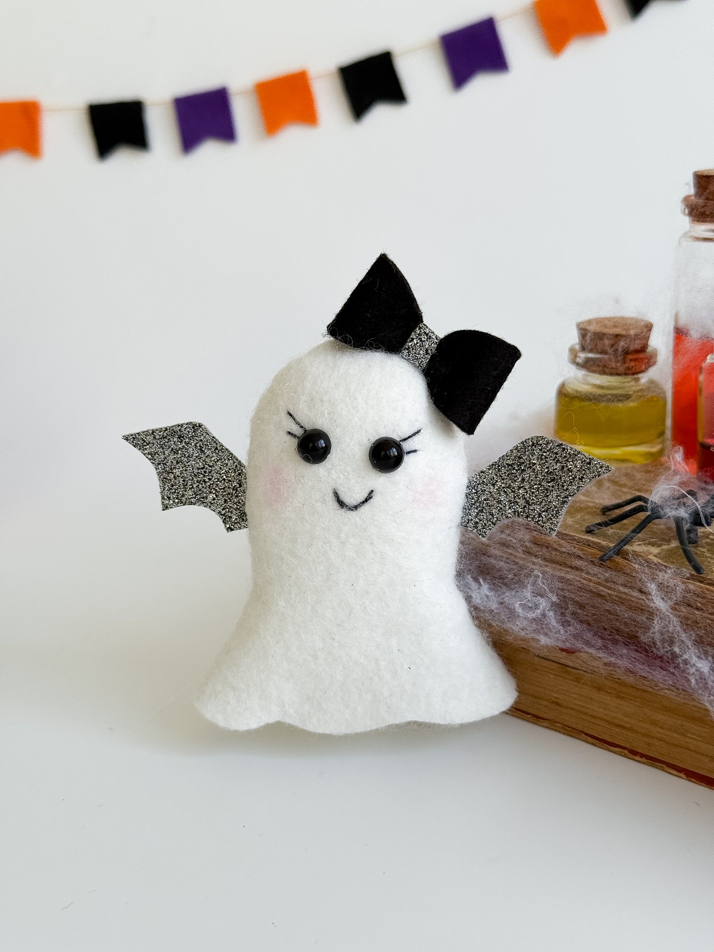 Spooky cute ghost plush ornament on Halloween-themed background