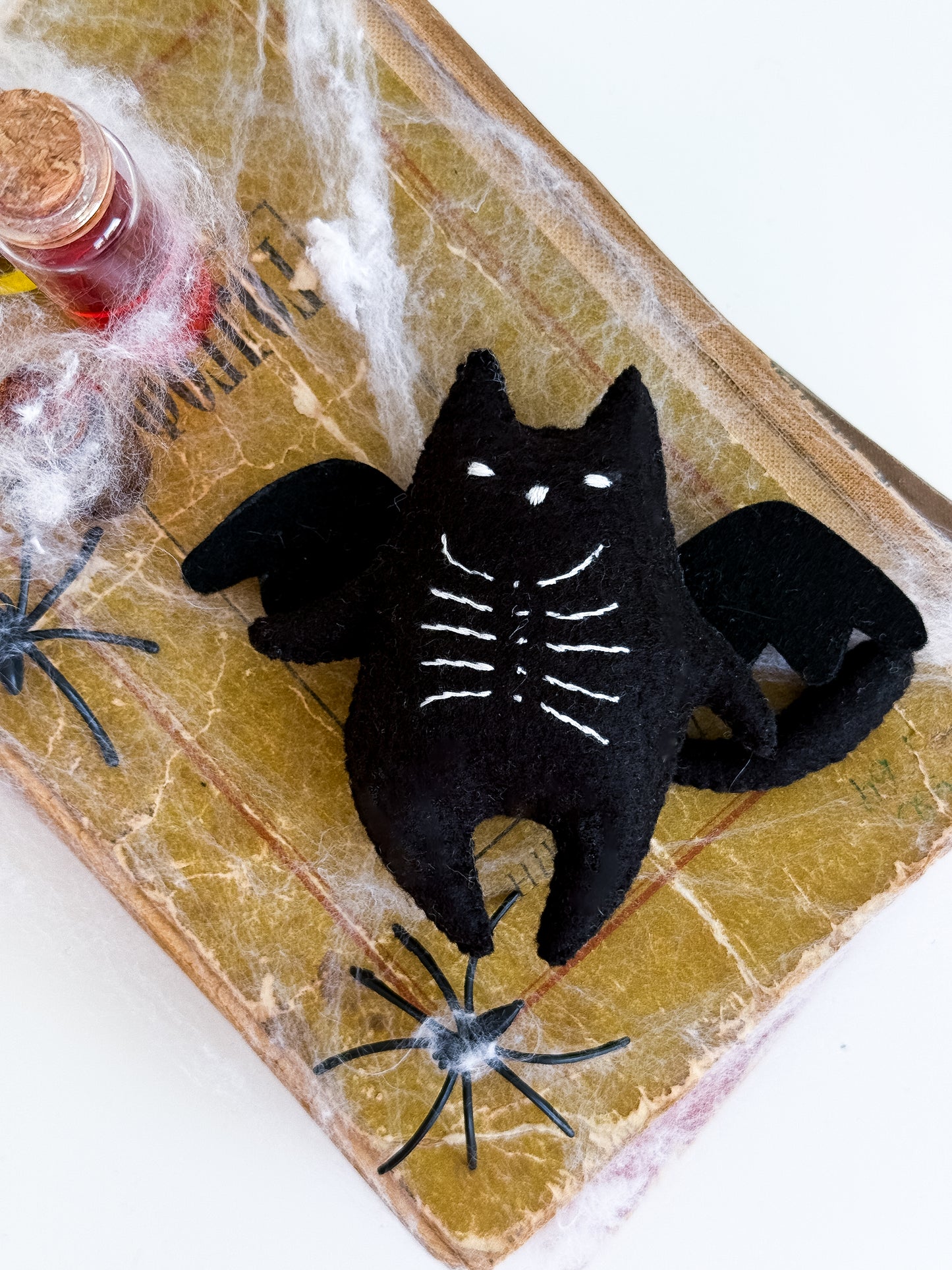 Felt black cat with embroidered bones and bat wings