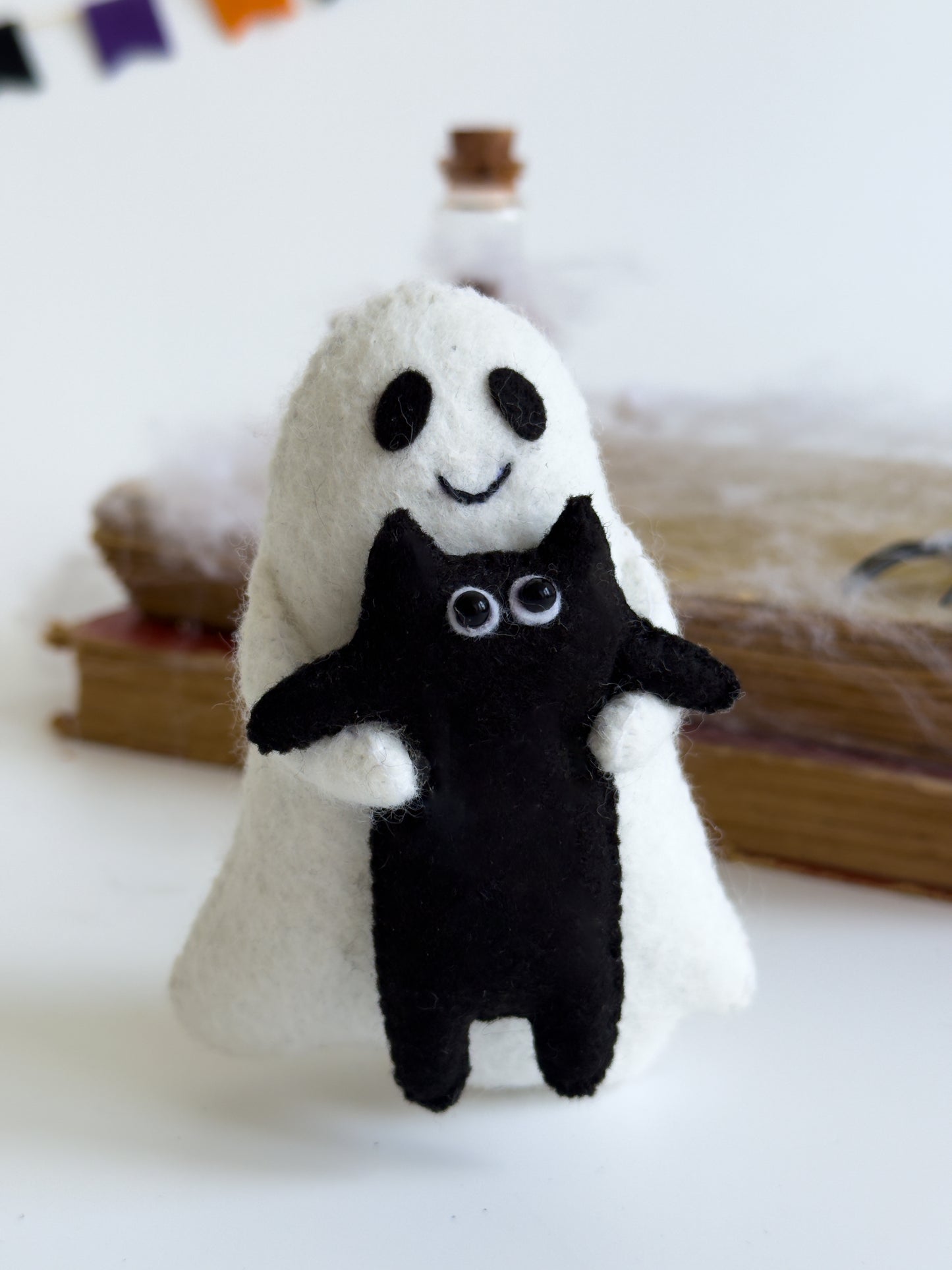 Ghost plush toy with stitched smile and hugging black kitty