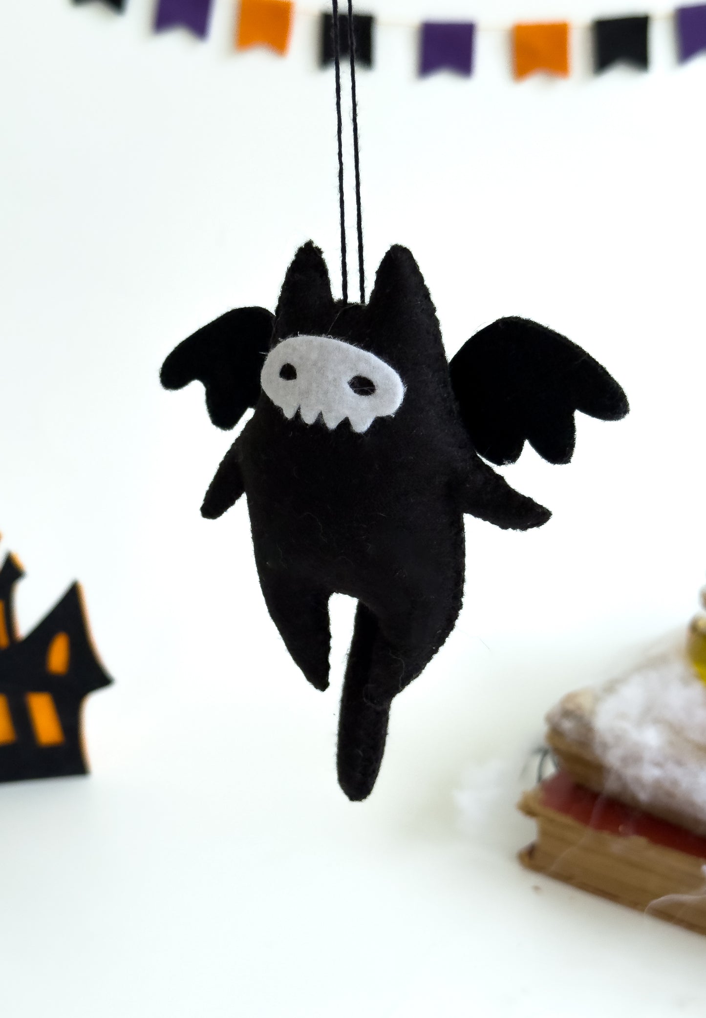 Close-up of felt cat toy with white stitched skull mask