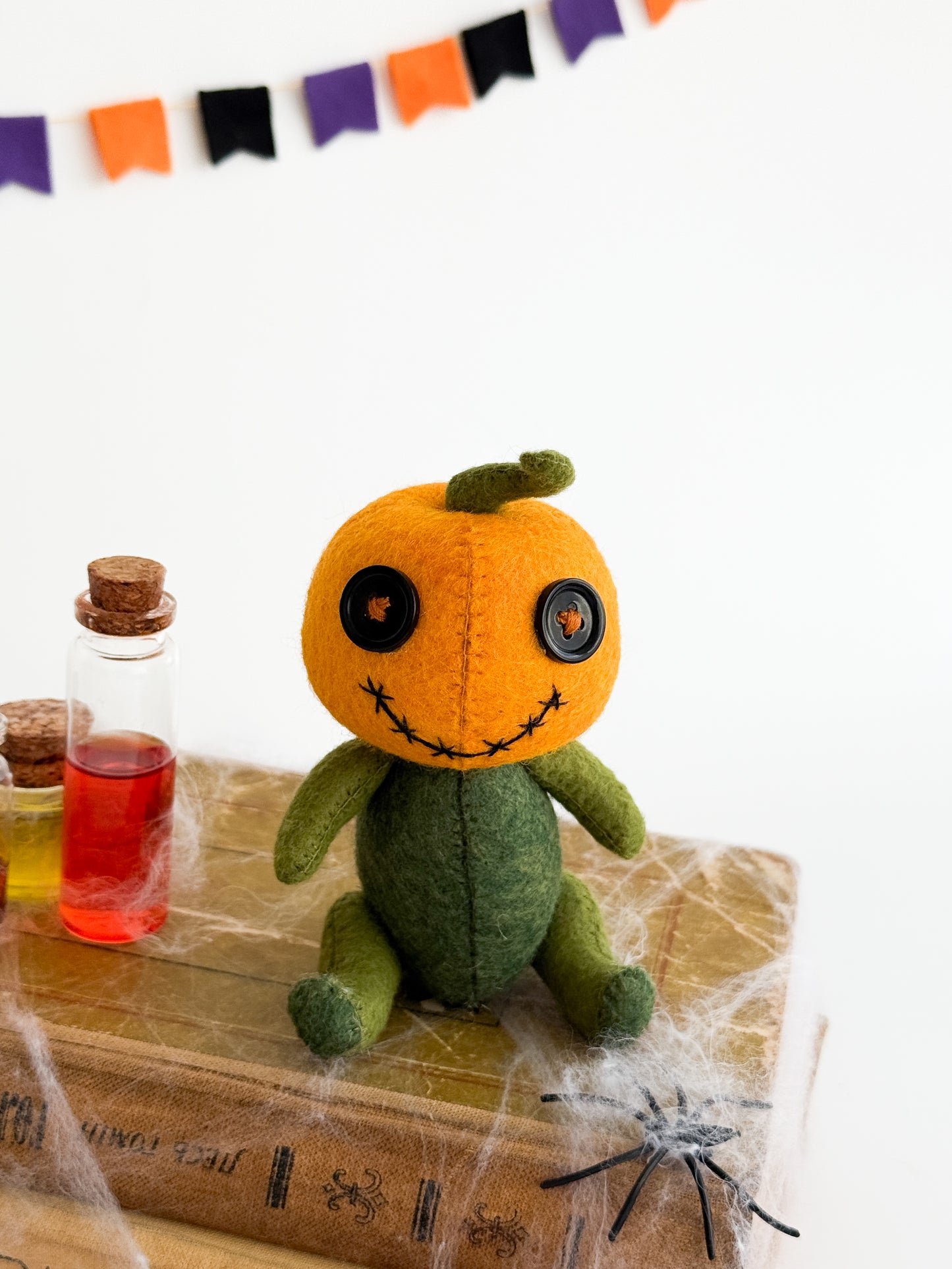 Orange felt pumpkin head plushie with green body