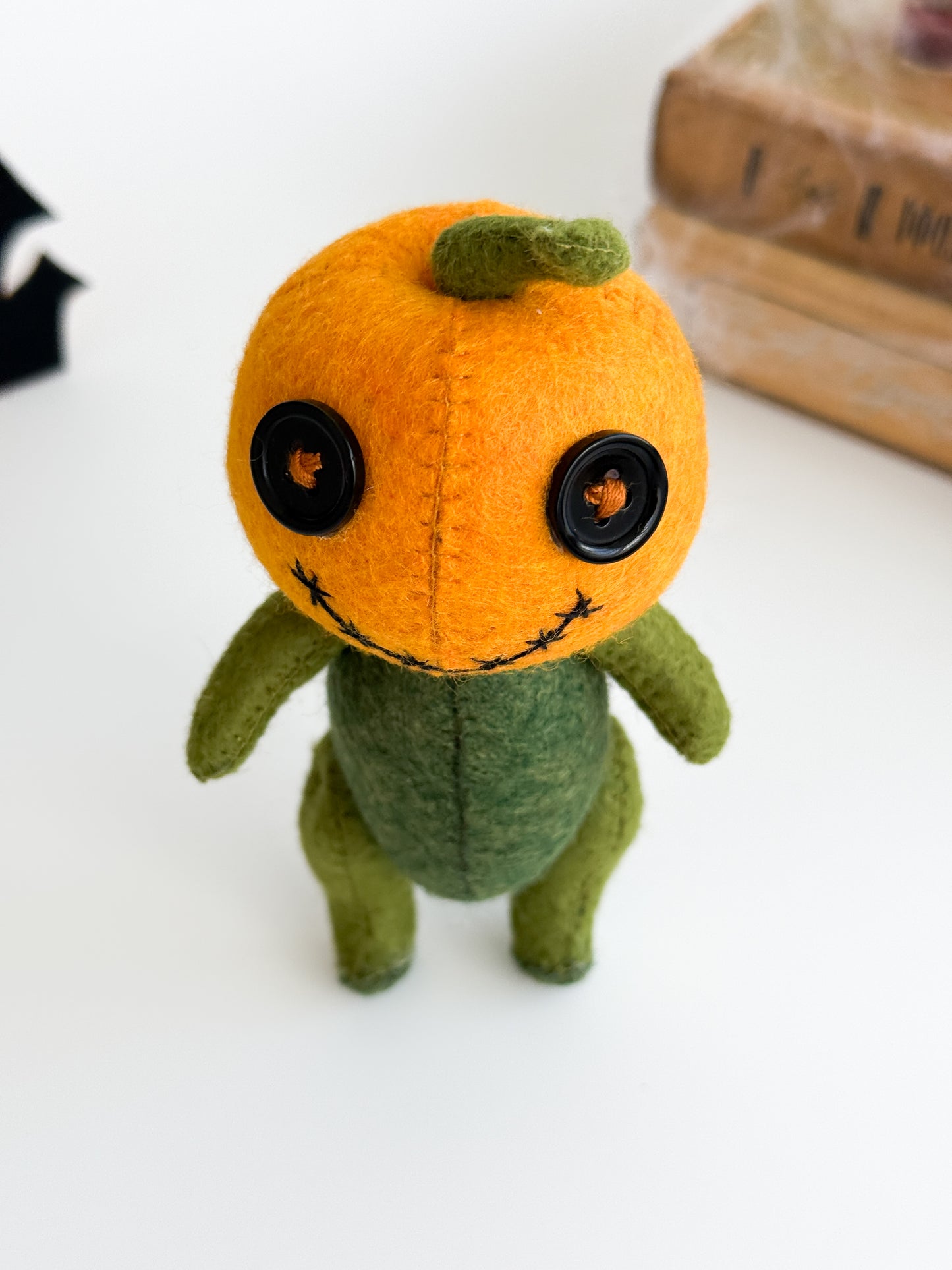 Orange felt pumpkin head plushie with green body