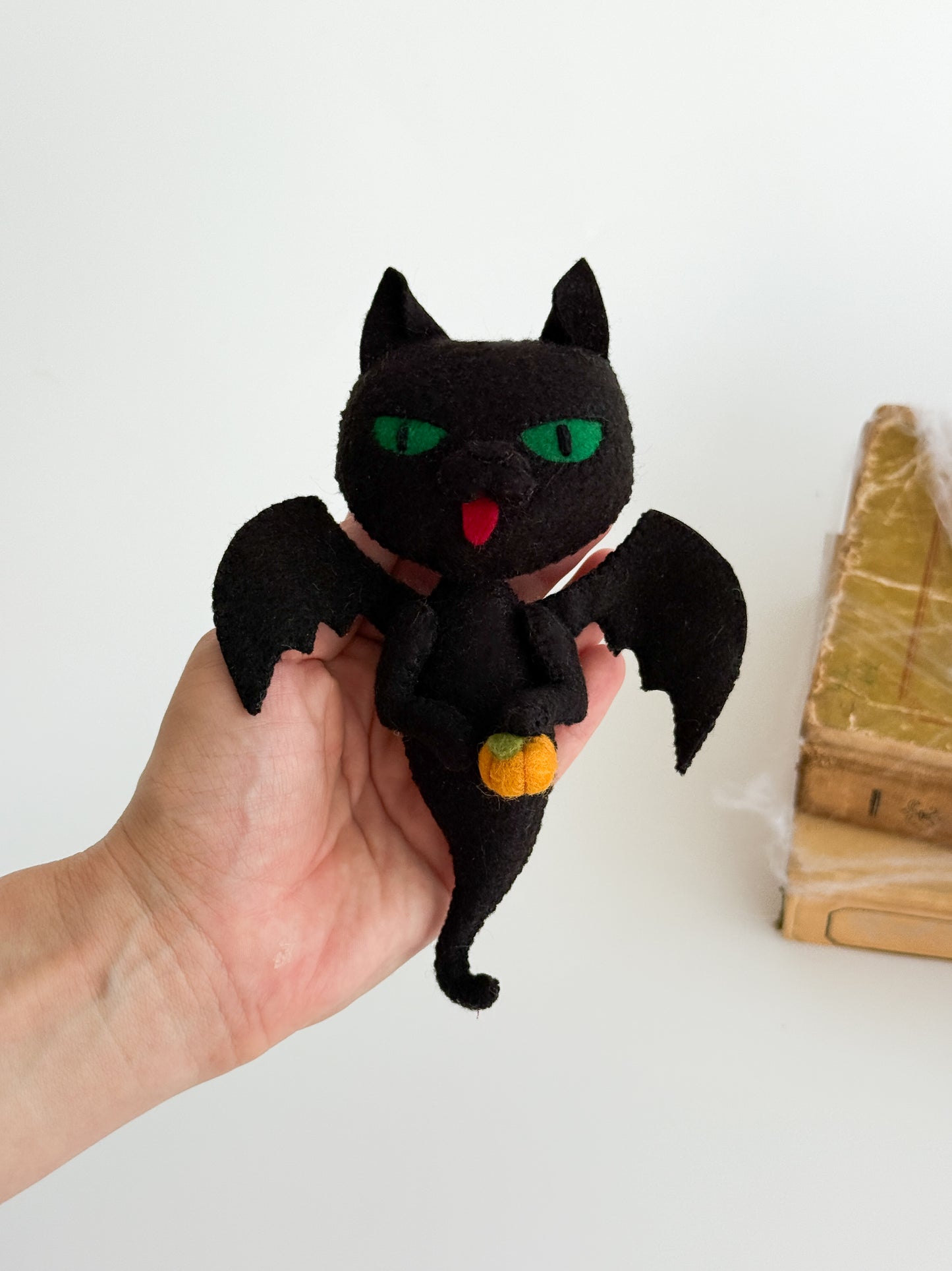 Spooky cute black cat ghost in felt with embroidered details and pumpkin, perfect for Halloween décor.