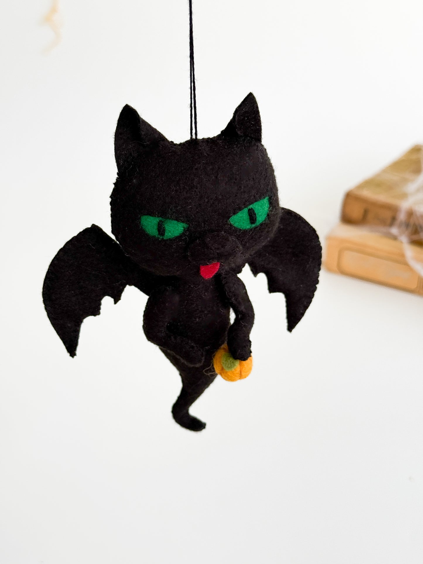 Handmade felt ornament of a black cat ghost hugging a pumpkin, autumn and Halloween home decoration.