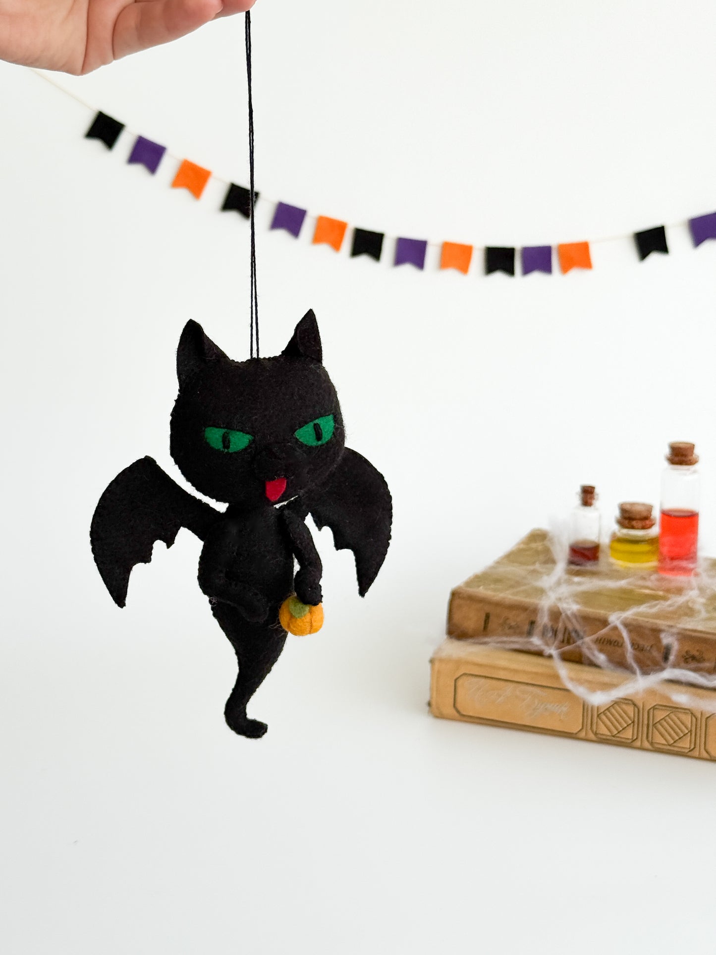 Felt black cat ghost with jack-o’-lantern pumpkin, handcrafted spooky ornament for festive seasonal décor.
