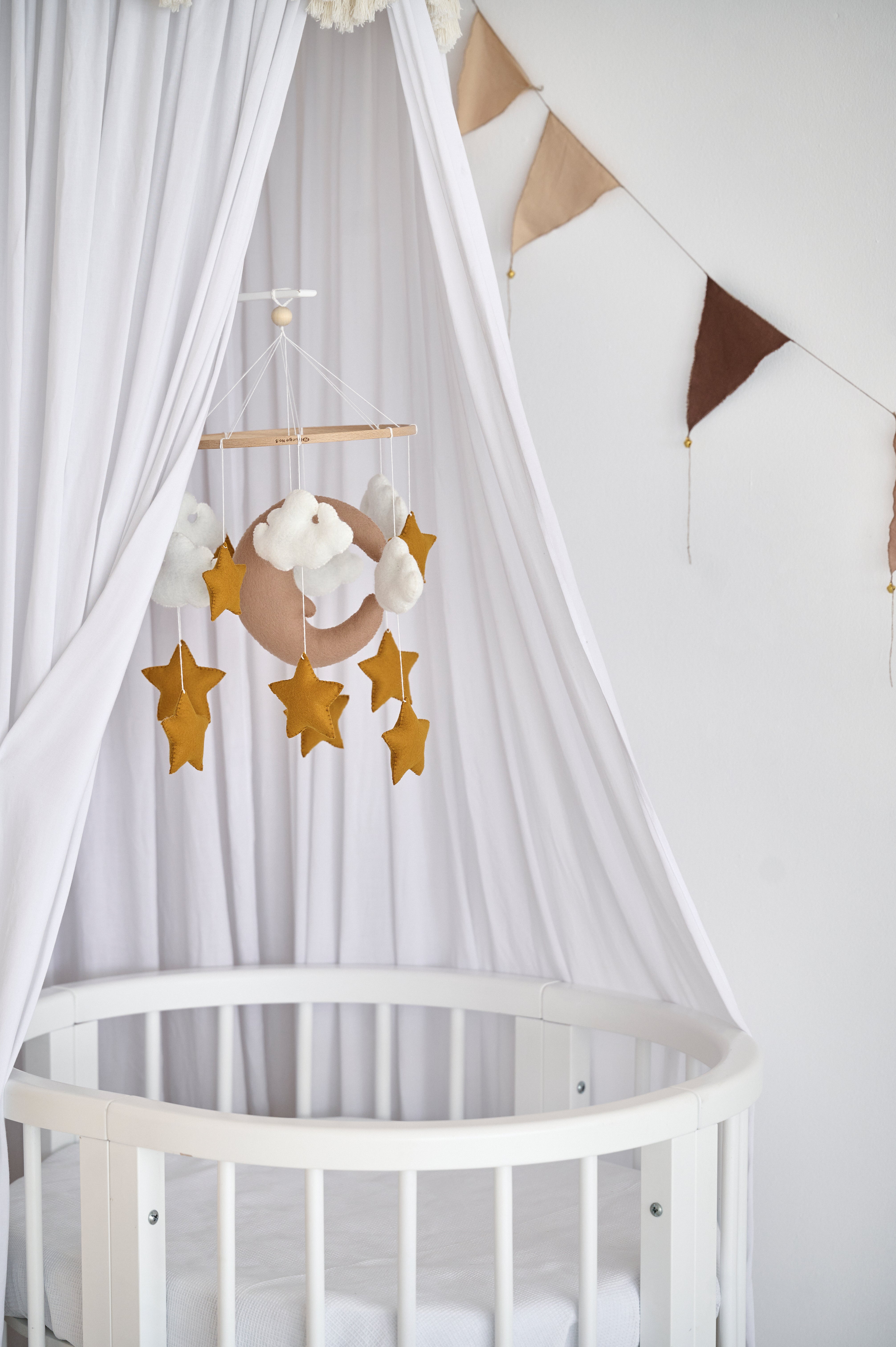 Beige baby mobile with moon, clouds, and stars above crib