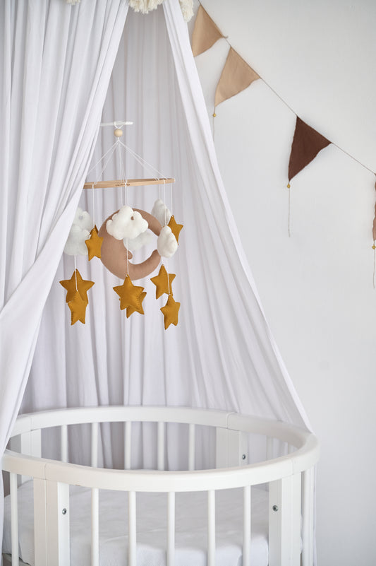 Beige baby mobile with moon, clouds, and stars above crib