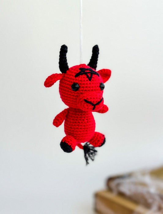 Handmade red Baphomet crochet plush with black horns, sitting on a white background