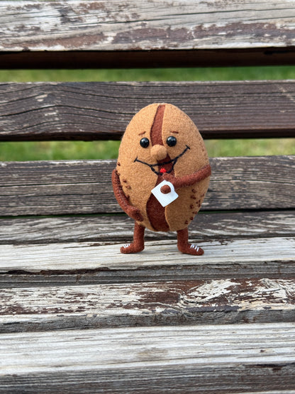 Close-up of cute coffee bean plush holding a small coffee cup