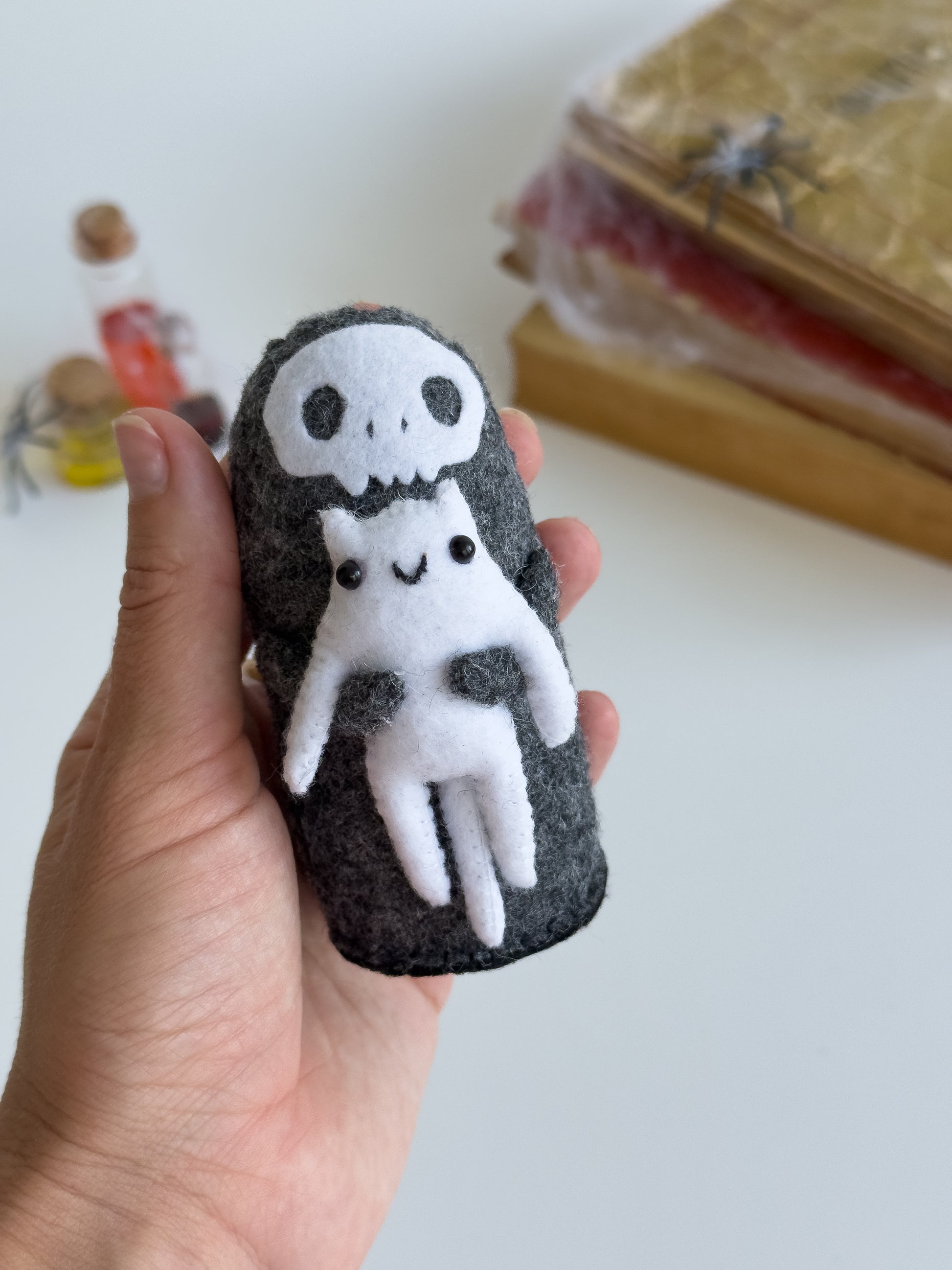 Close-up of Grim Reaper Halloween plush with tiny smiling white cat