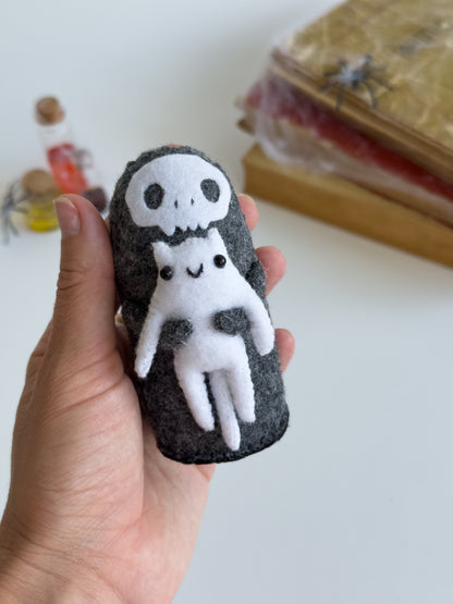 Close-up of Grim Reaper Halloween plush with tiny smiling white cat