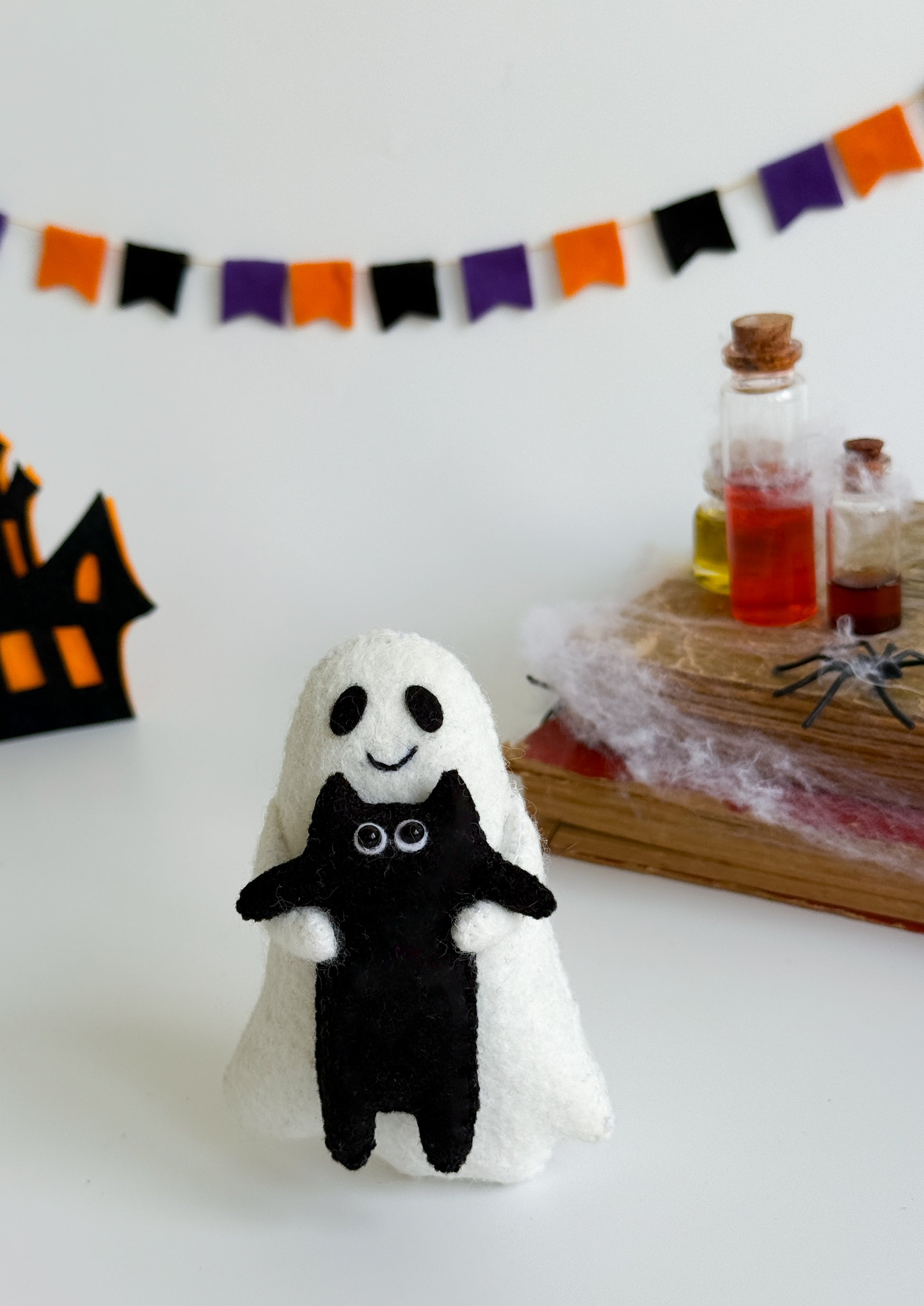 Ghost plush toy with stitched smile and hugging black kitty