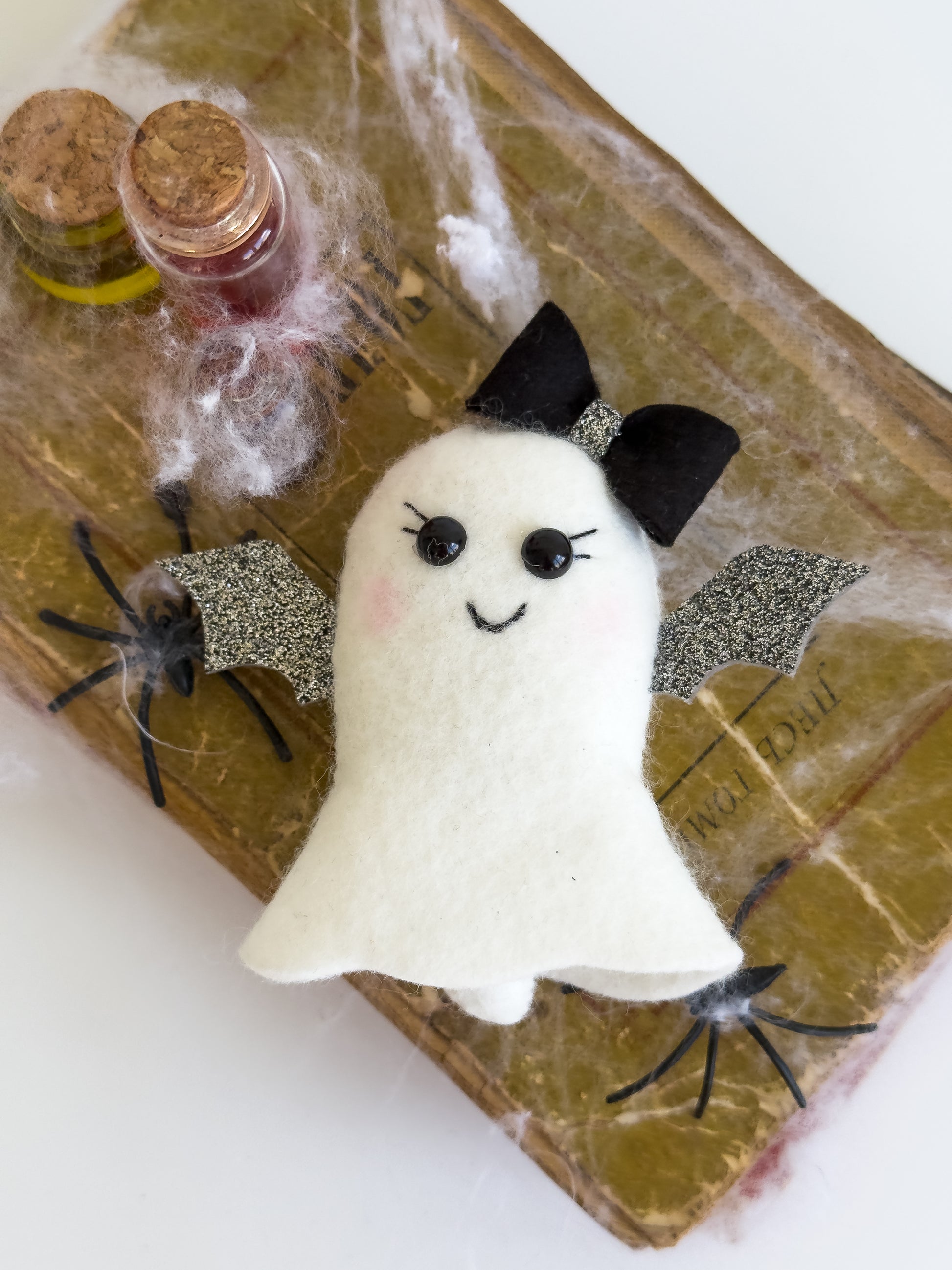Spooky cute ghost plush ornament on Halloween-themed background