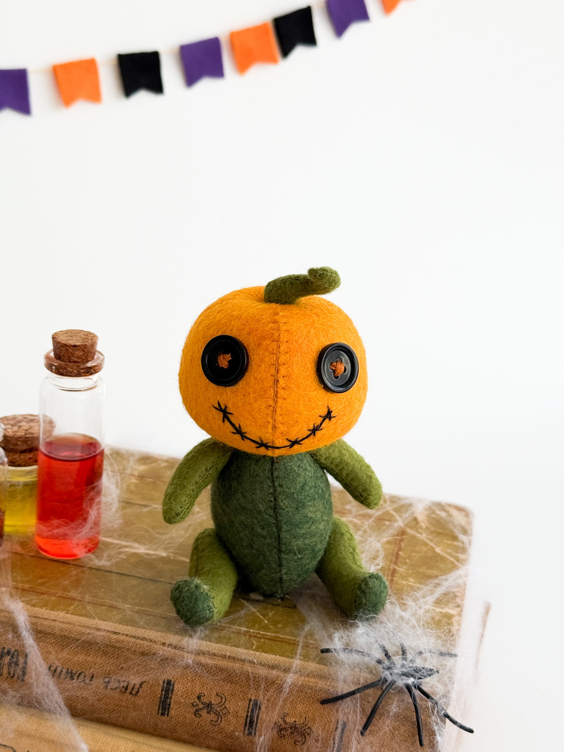 Orange felt pumpkin head plushie with green body